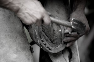 Blacksmith attaching horseshoe to horse's hoof - close-up